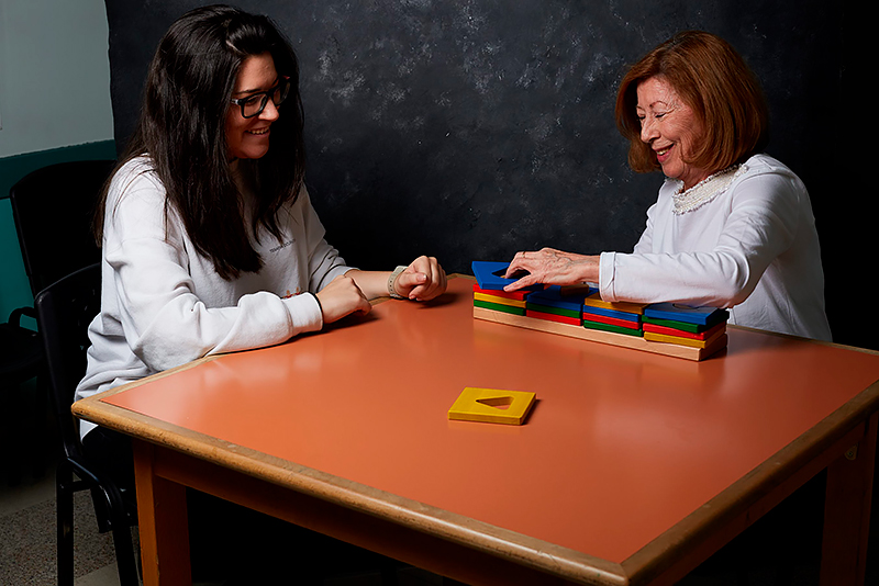 Dos mujeres sentadas en una mesa hacen ejercicios con bloques de colores