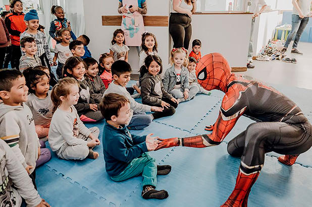 Spiderman playing with a group of seated children
